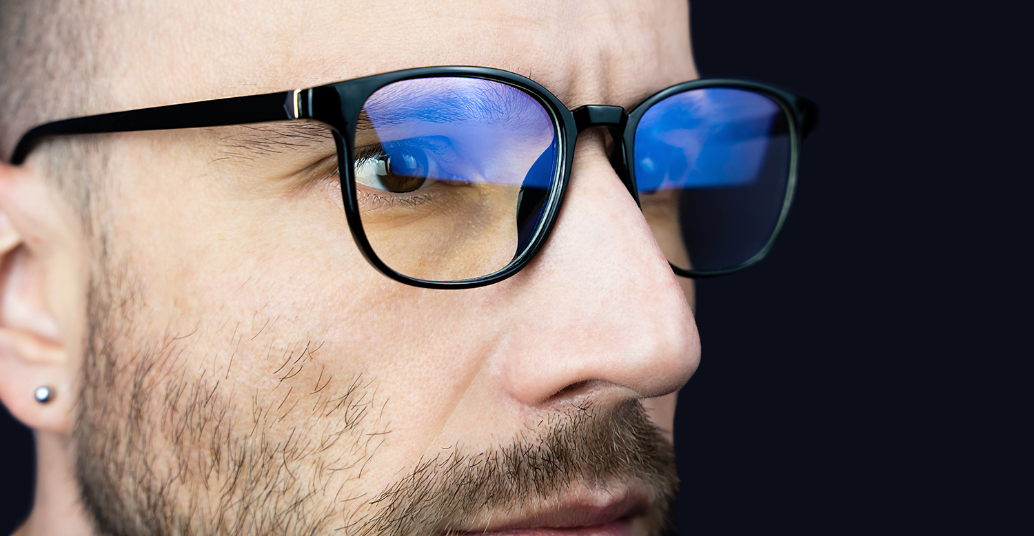 Nærbilde av en mann med briller som ser på en dataskjerm