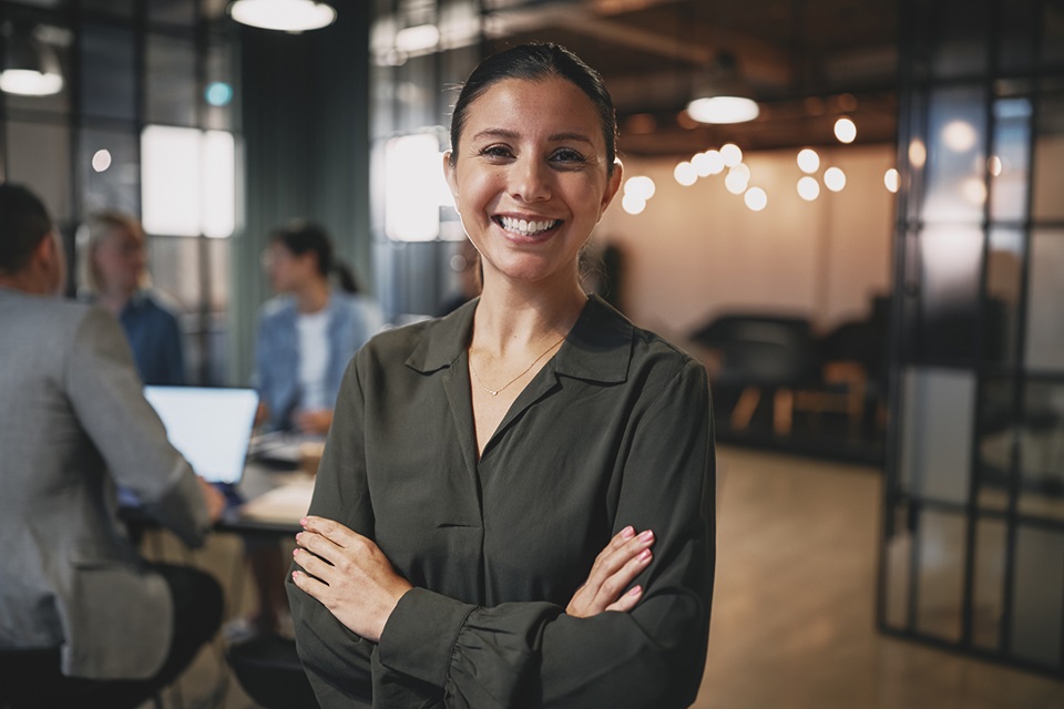En kvinne smiler mot kamera i et moderne kontormiljø