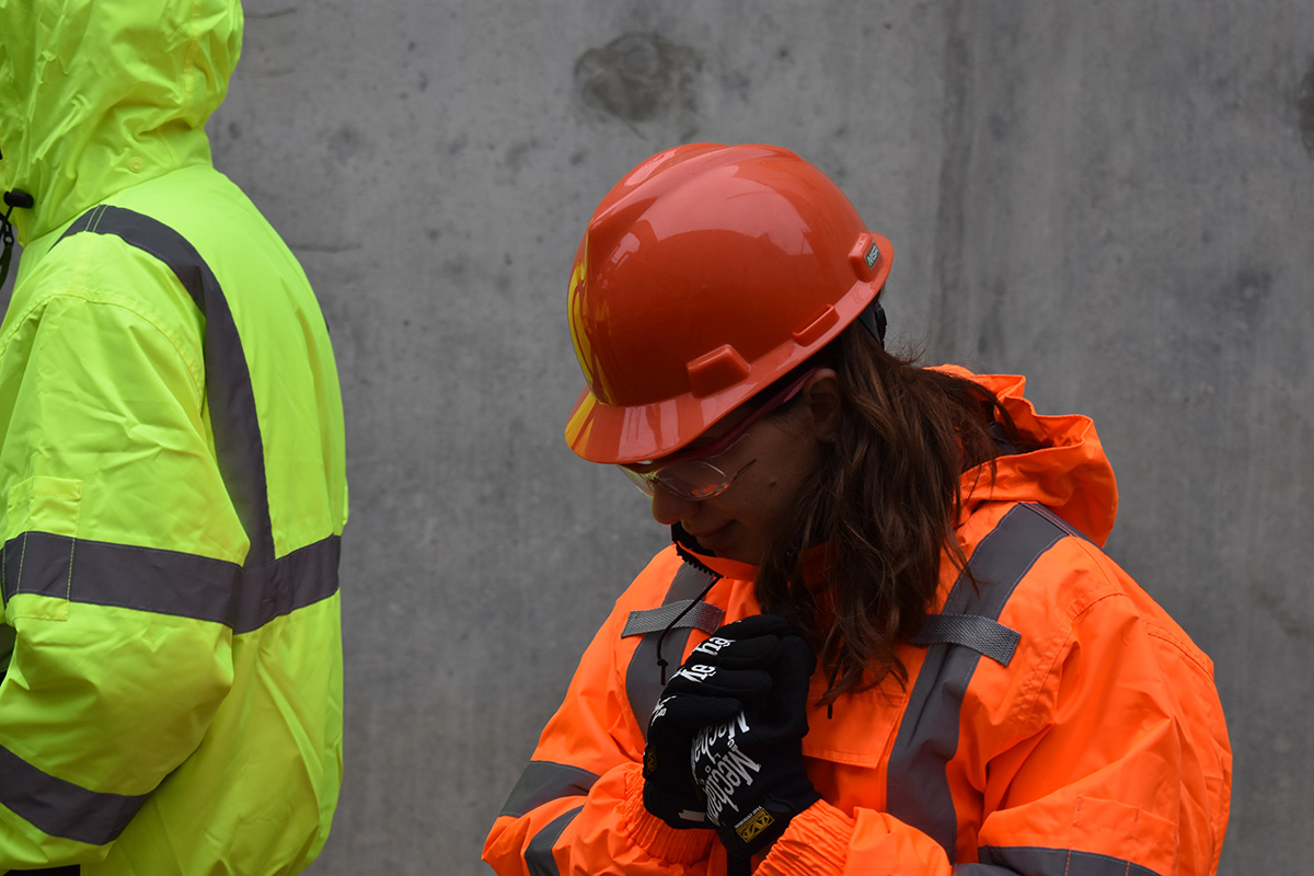 En kvinne iført hjelm og arbeidsklær på en byggeplass.