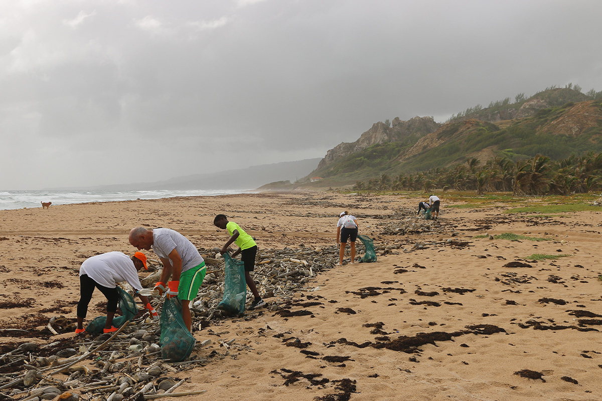 En gruppe mennesker rydder søppel på en strand. Foto.